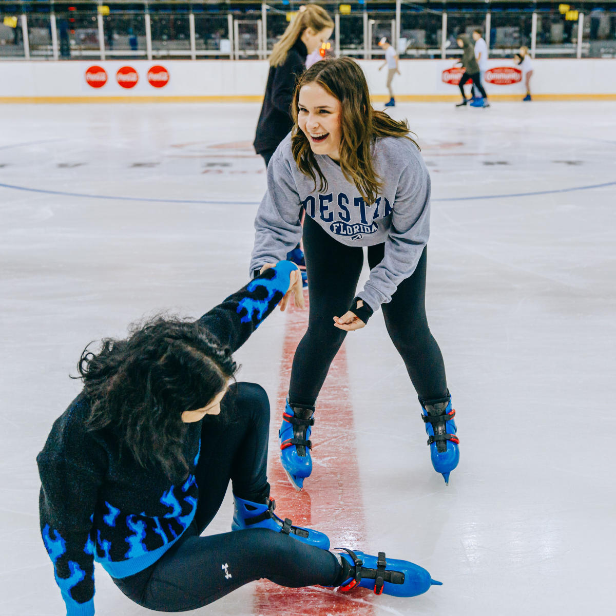 在河中心滑冰时，一个女孩扶着另一个女孩