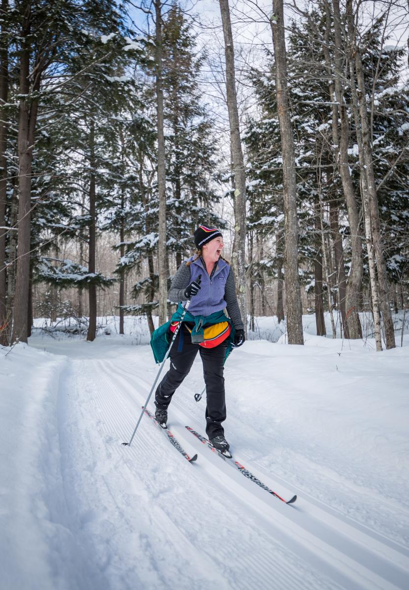 A woman smiling while cross country skiing in Big Bay, MI