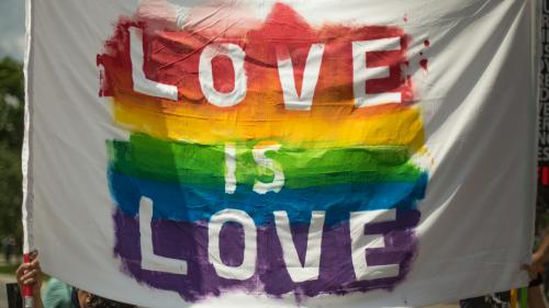 Love is love sign painted in white letters over rainbow colors
