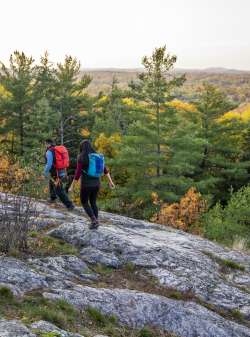 A Couple standing on a rock atop hg6668皇冠登录山 surrounded by orange, red, 黄色的秋叶.