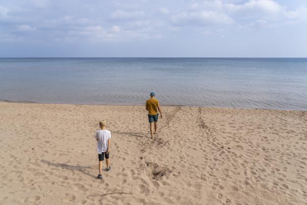 A father and son walking out to the 苏必利尔湖 shoreline at Little 普雷斯克 beach