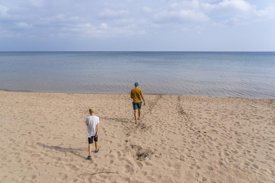 A father and son walking out to the 苏必利尔湖 shoreline at Little Presque beach