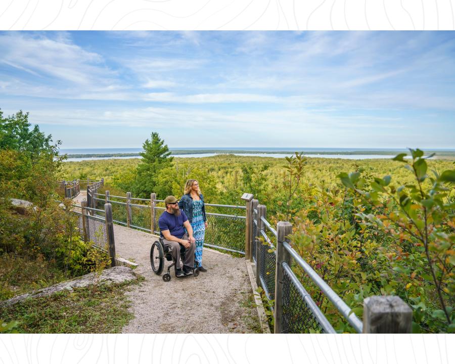 A man in a wheelchair and a woman looking out at the overlook at Thomas Rock in Big Bay