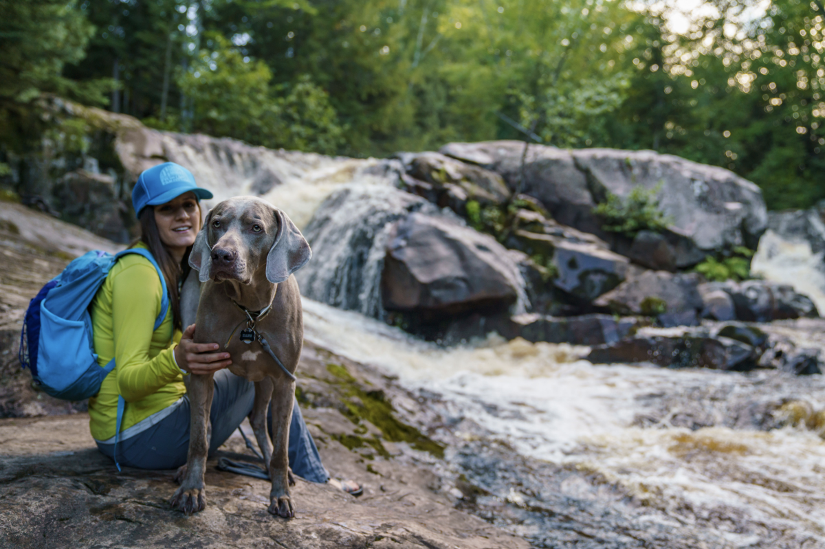 A woman and her dog in front of Yellow Dog Falls in Big Bay