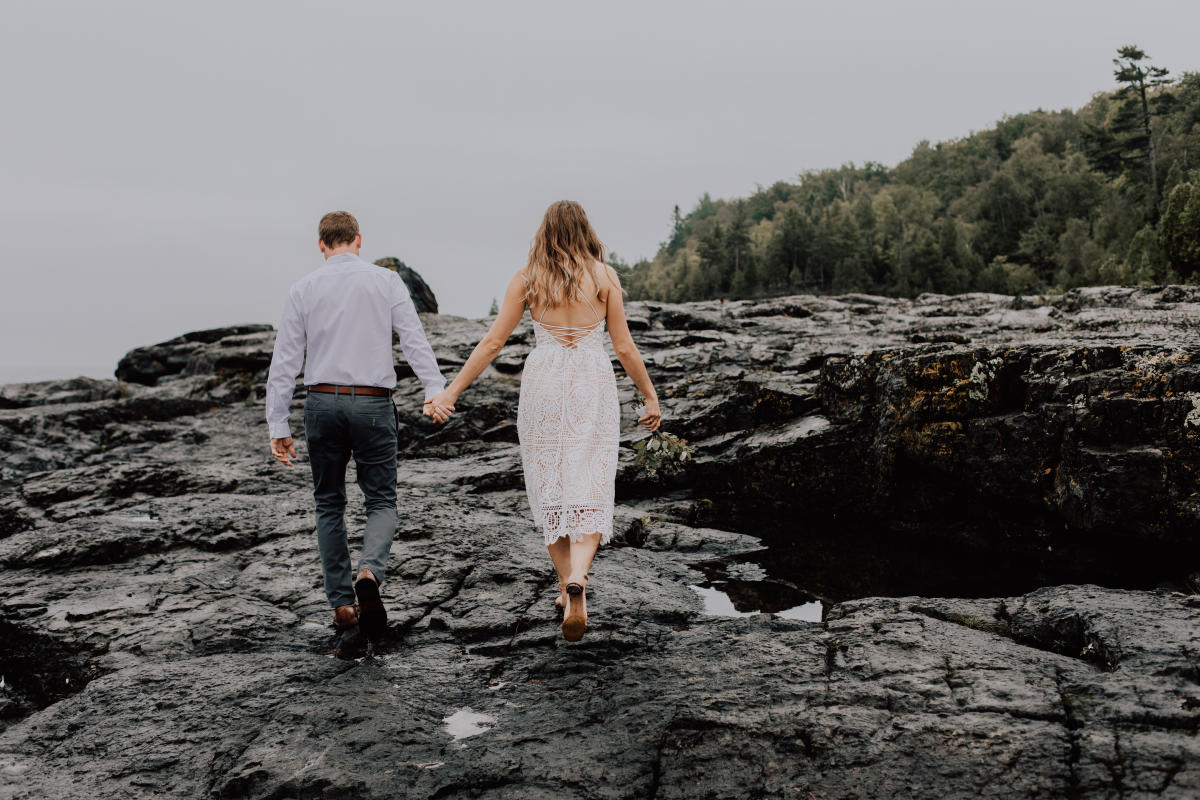 A newlywed couple holds hands on the Black Rocks in Marquette