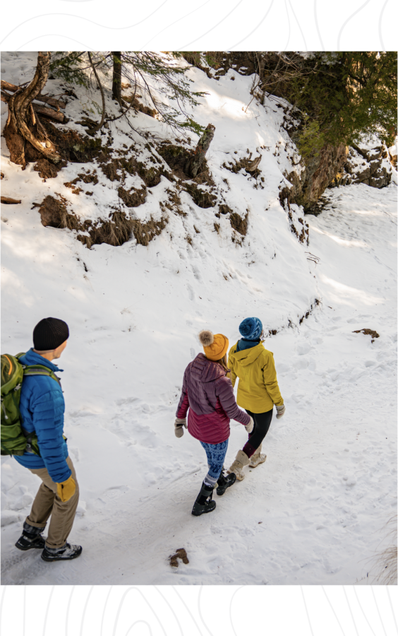 A group of three friends hiking on the snow-packed trail at 普雷斯克岛公园 in hg6668皇冠登录, MI