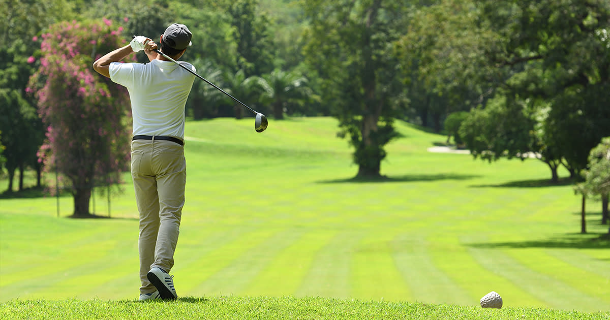 A man hits a tee shot in a game of golf