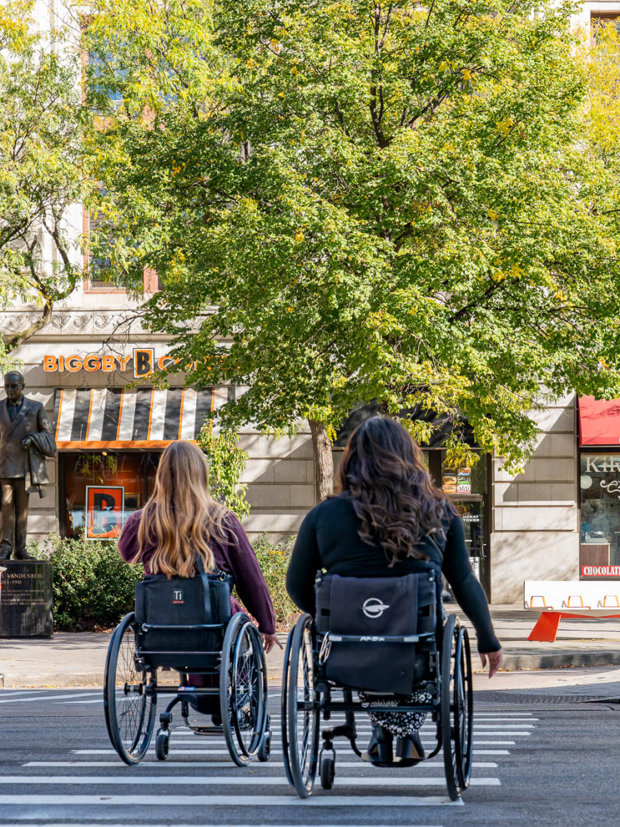 2 wheelchair users crossing a street in downtown Grand Rapids.