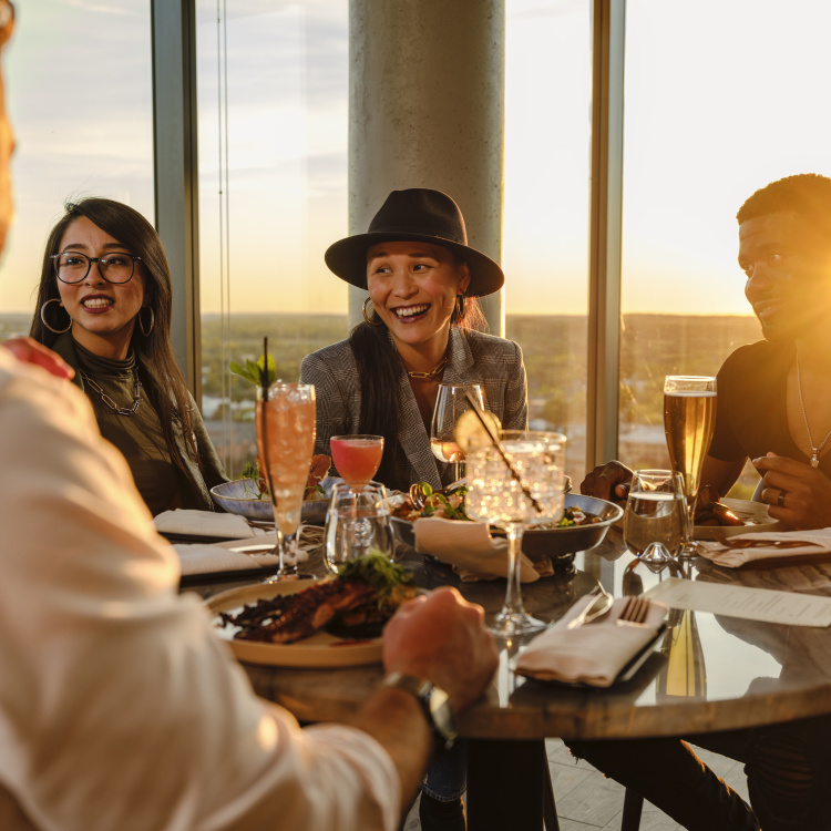 Group of people dining at MDRD on top of the Amway Grand Plaza at sunset.