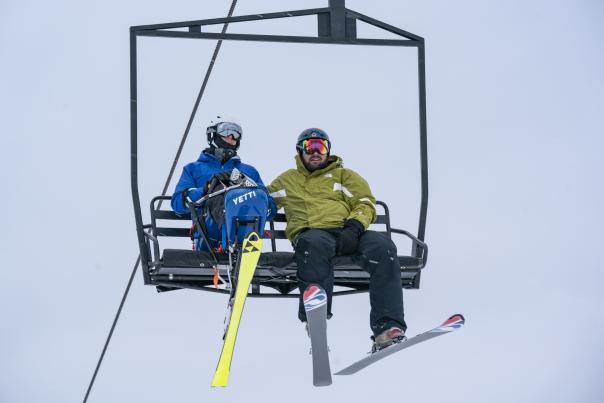 Two skiers waiting to go up on the ski lift at Cannonsburg Ski Area. One with adaptive ski equipment.