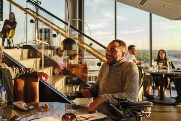 Group of people dining at MDRD on top of the Amway Grand Plaza at sunset.