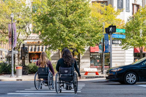 2 wheelchair users crossing a street in downtown Grand Rapids.