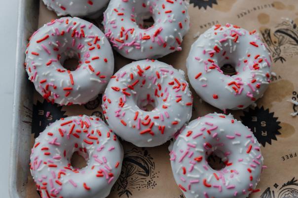 A tray of freshly baked white donuts with a sprinkling of red sprinkles, at Rise Bakery.