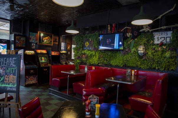 The eclectic inside of Stella's Lounge with red booth seating, checkered floors, and arcade games.