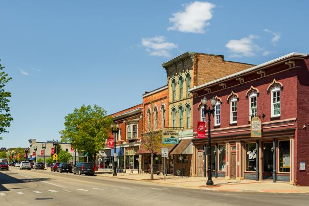 A quiet street with historic buildings lining both sides stretches into the distance under a clear blue sky.