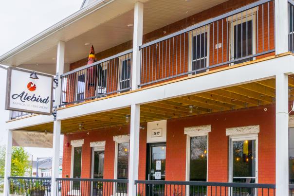 Exterior of Alebird Taphouse & Brewery, which is in a red, two-story building.