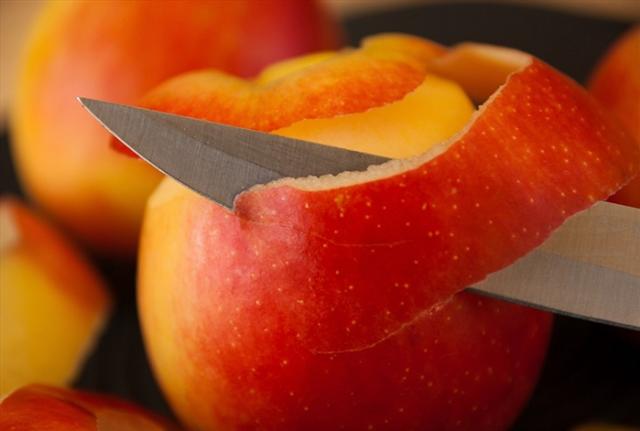 An apple being peeled with a knife