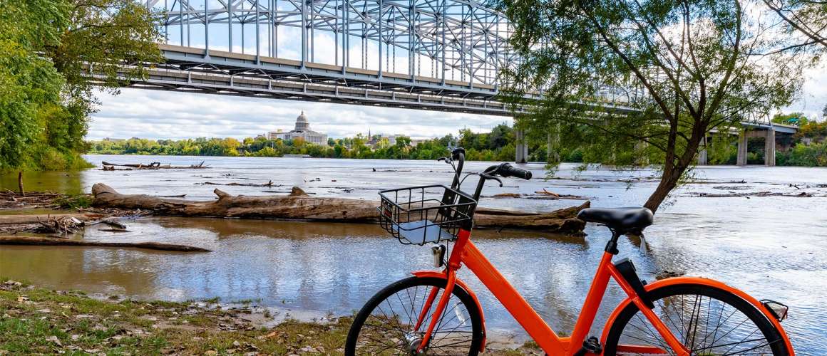 Bike next to a river with a bridge in the background