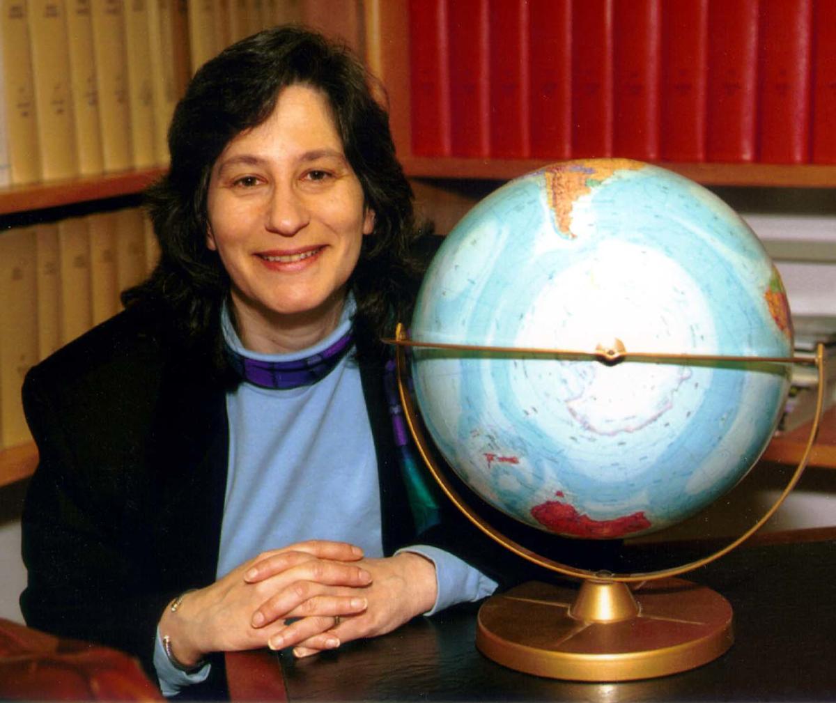 Head shot of Susan Solomon sitting next to a globe