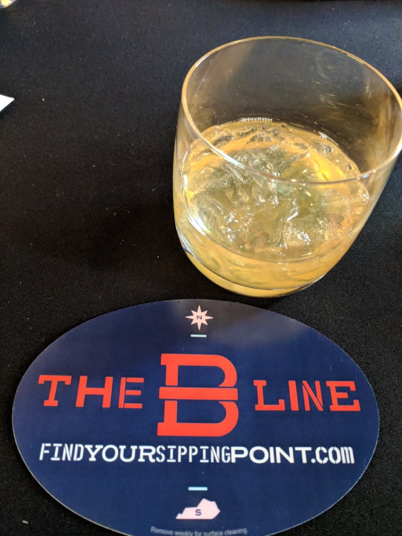 The B-Line cocktail in a bourbon glass next to a blue, red and white coaster for the B-Line