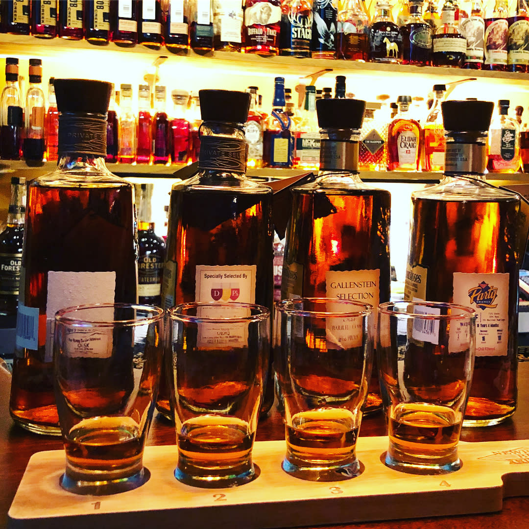 Four bottles of bourbon on bar in front of Prohibition Bourbon Bar's huge bourbon collection