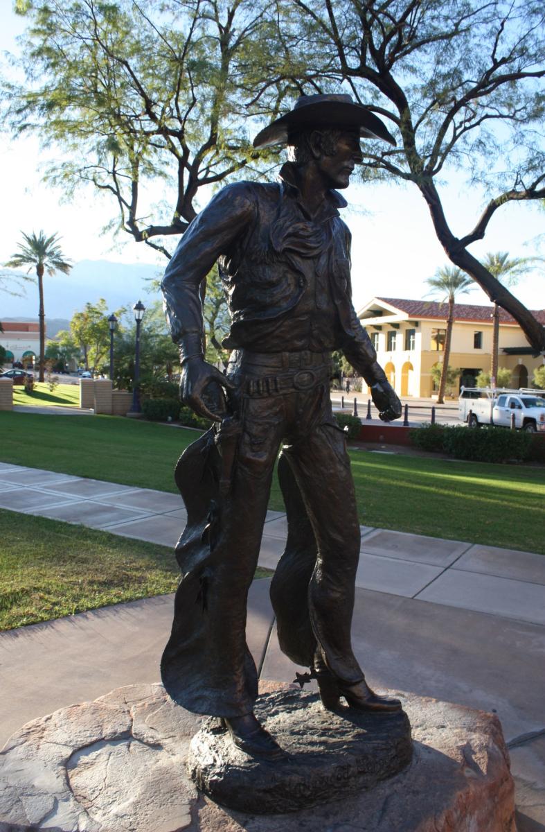 Bronze statue of a man wearing a cowboy hat