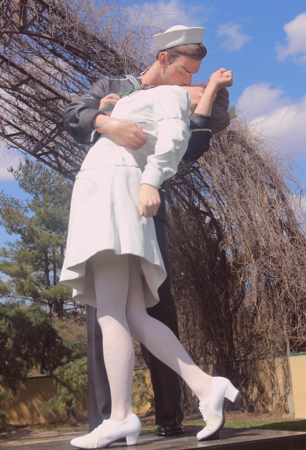 a larger than life sculpture of a sailor kissing a woman in a white dress