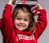 A young girl wearing UW apparel holds books over her head