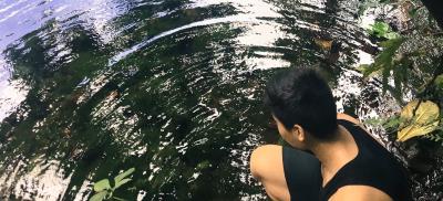 Hiker crouching at edge of the Lost Pond in Guam