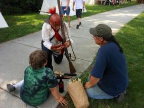 An American Indian interpreter discusses corn with two  visitors at the Siege of 1812