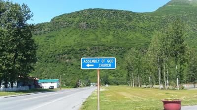 a street sign pointing to an Assembly of God church