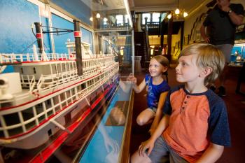 Two children looking at a steamboat display in the Howard Steamboat Museum.