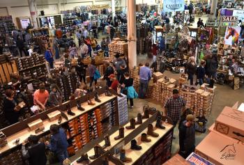 View from above of customers shopping among cowboy boots, horse tack and supplies at Equine Affaire's trade show