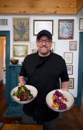 Man Holding Two Plates Of Food In Portage House