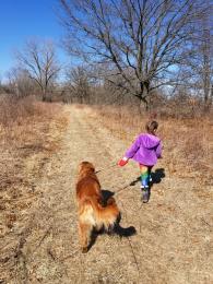 girl walking dog on trail