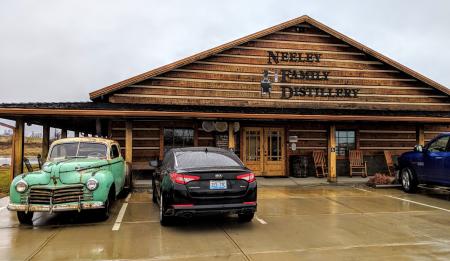 The exterior of Neeley Family Distillery, a wood building on the B-Line Bourbon trail in NKY, with an old bootlegger's car parked out front.