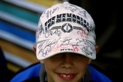Kid at the Memorial Tournament showing off his hat signed by pro golfers.