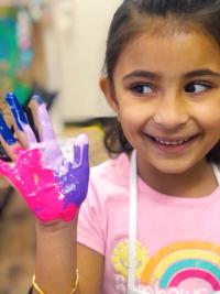 Brightly Art Studio is offering virtual art classes. Girl with paint on hand