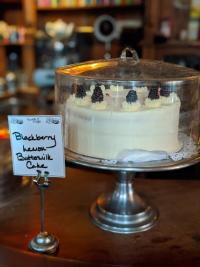 photo of a cake on a cake stand with a sign that says blueberry lemon buttermilk cake at york street cafe in newport ky
