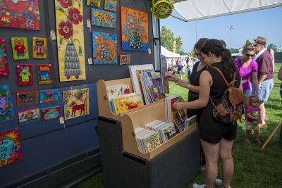 Women examining art at UA Labor Day Arts Festival outdoors