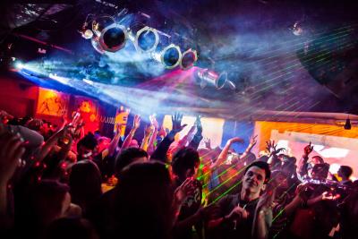 Crowded nightclub dance floor with colorful laser lights & fog over dancers