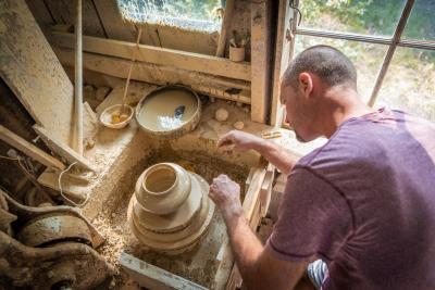 A man crafting pottery in a studio.