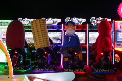 Four mascots sit in front of screens in an arcade.