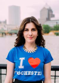 Rachel stands infront of the Genesee River wearing a "I Heart Rochester" T-shirt