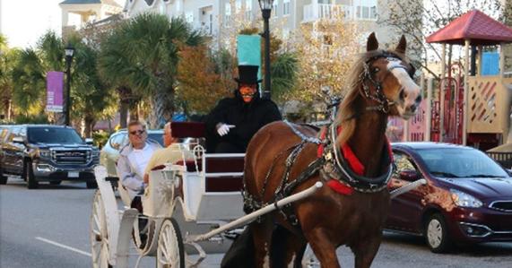 A costumed driver leads a horse-drawn carriage during Market Common Haunted Carriages Rides