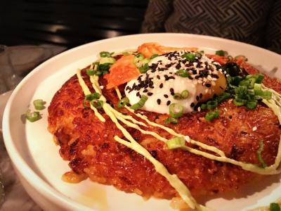 Dish of crispy fried rice topped with soft egg, greens, and a drizzle of sauce from Comune Restaurant