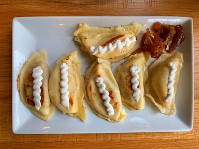 Pierogis topped with sauce on white plate from Pierogi Mountain