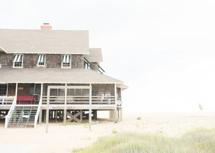 A vacation rental home sits right on the shore with stairs leading straight into the sand.