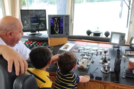 riverboat captain and two children at the controls of the vessel during bb riverboat cruise on the ohio river