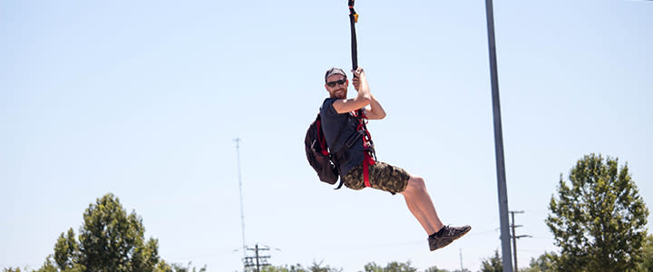 A visitor's face lights up as they ride the SandRidge SkyZip at the Boathouse District along the Oklahoma River.